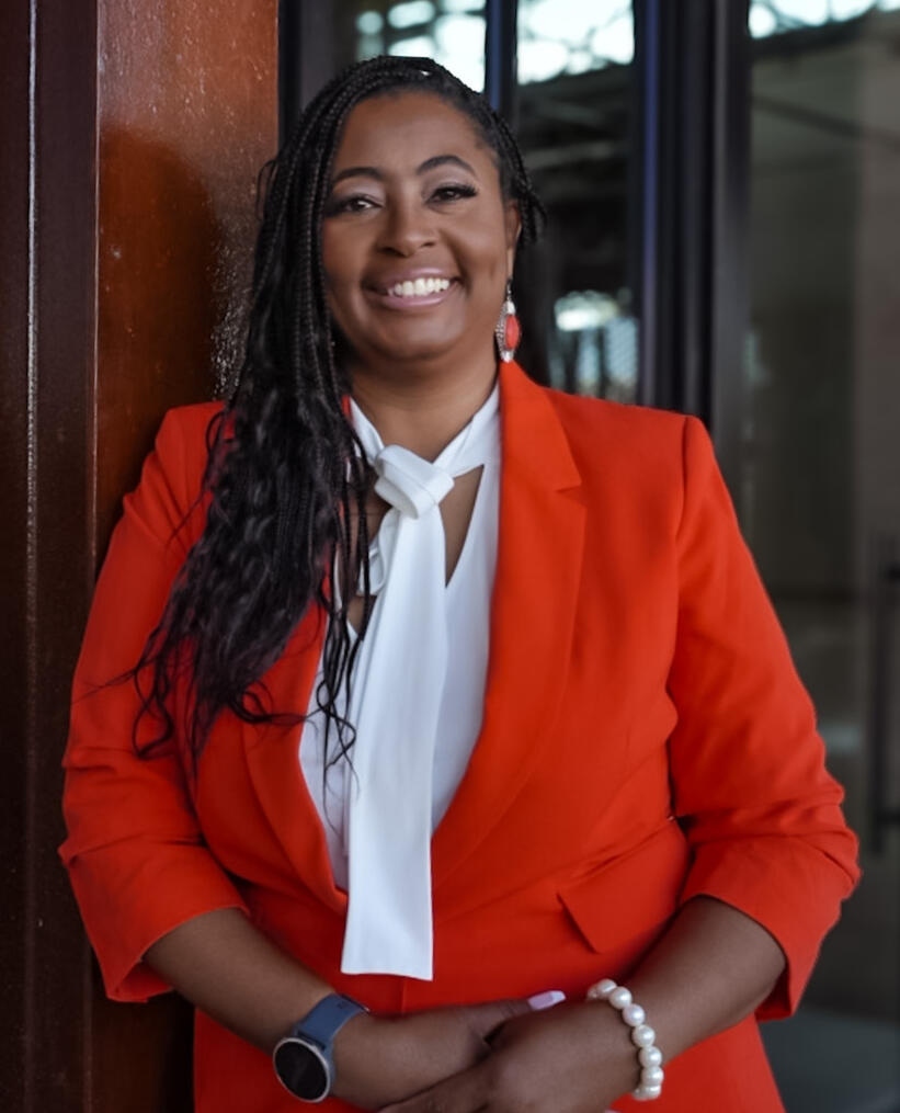 Marlene Lawson, CEO & Founder, wearing an orange blazer and smiling to the calendar